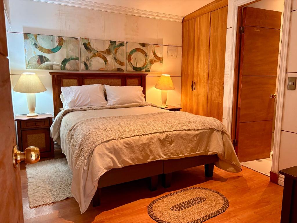 a bedroom with a bed with two lamps and a painting at Casa Nilhue junto al río in Lo Barnechea