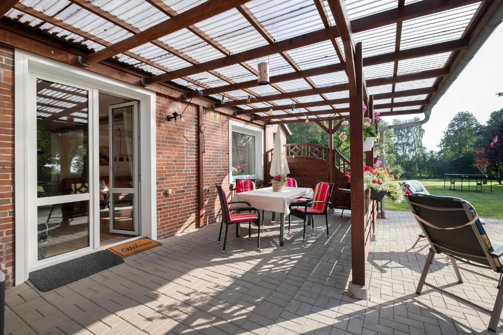 a patio with a wooden pergola with a table and chairs at Bi Tiessens to Hus in Arkebek
