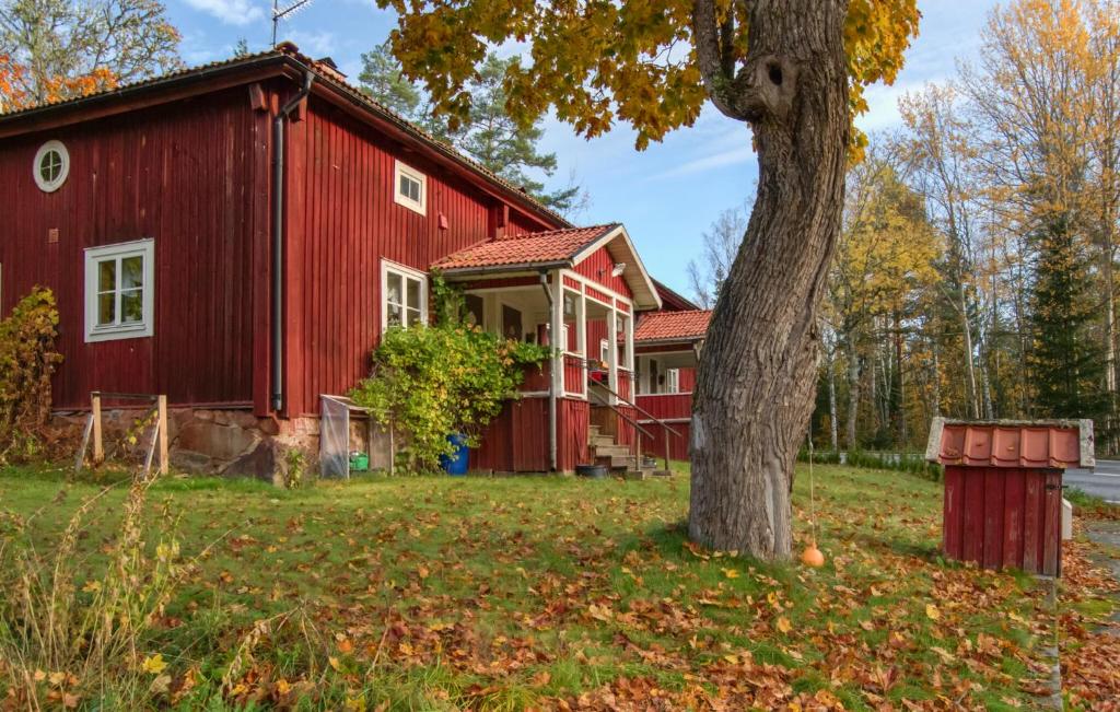 a red barn with a tree in front of it at Pet Friendly Home In Kopparberg With Lake View in Kopparberg