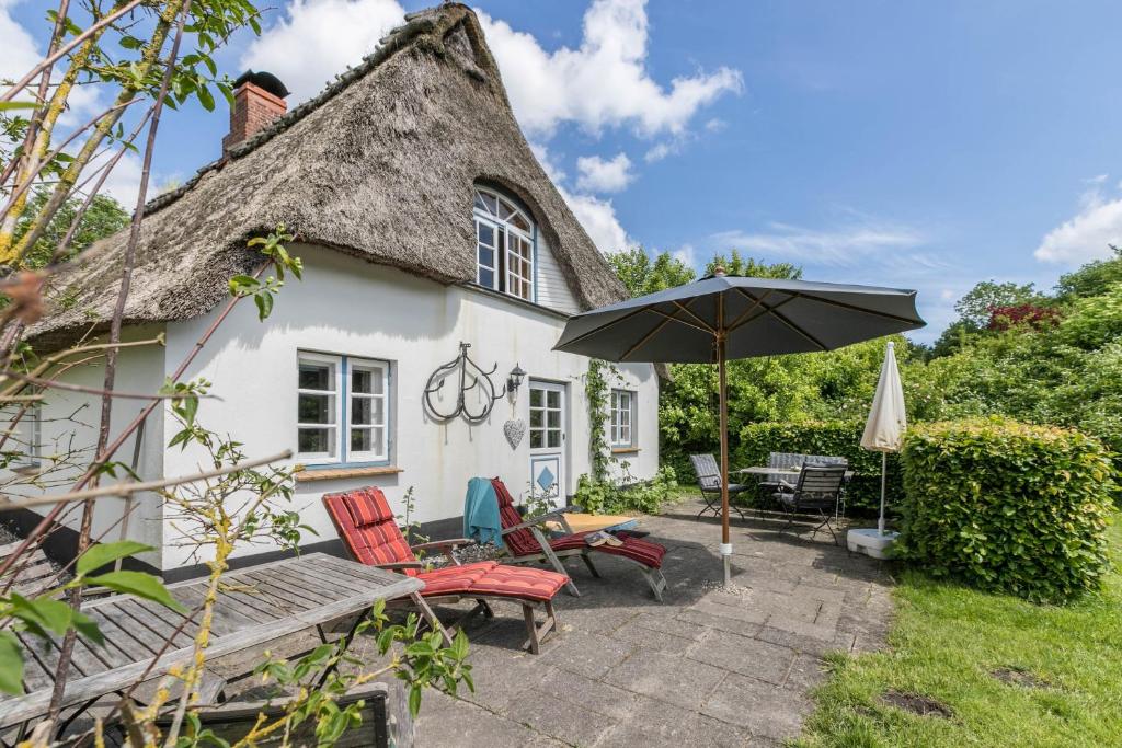 a cottage with a thatched roof and an umbrella at Ferienhaus Kleiner Knopp in Glücksburg