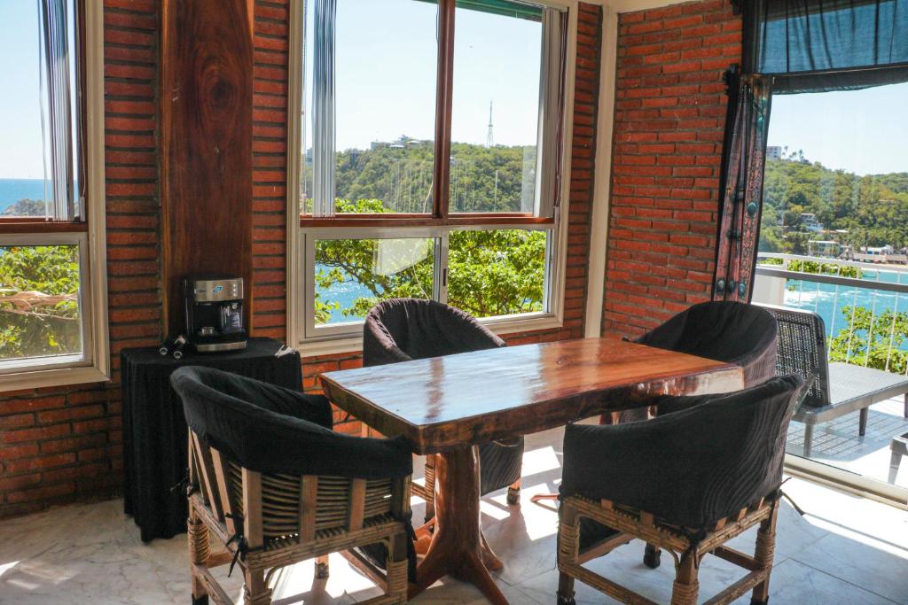 a wooden table and chairs in a room with windows at casa wow in Puerto Ángel