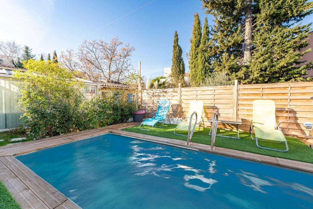 a swimming pool in a backyard with two chairs and a table at Le Chalet Houda et spa en option in Nîmes