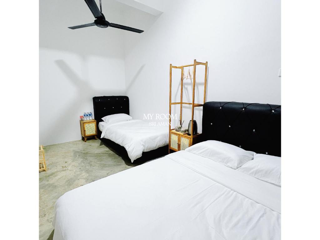 two beds in a room with white sheets at My Room Sri Aman in Kampong Lamanak