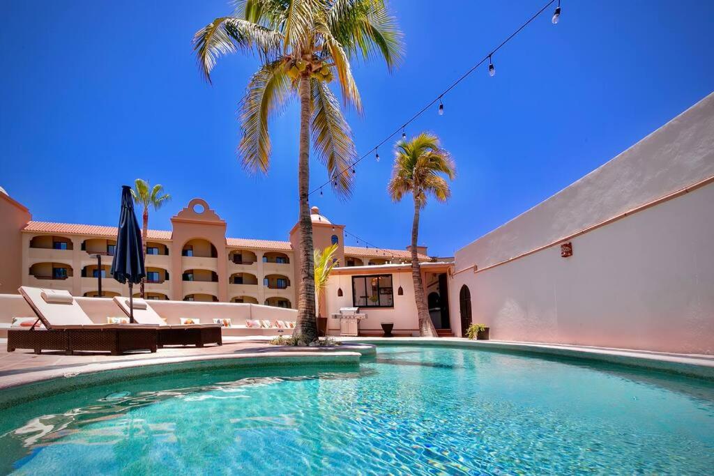 ein Swimmingpool vor einem Gebäude mit Palmen in der Unterkunft Los Cabos - Costa Azul Apartments in San José del Cabo