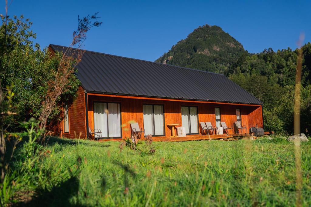 a wooden cabin with chairs in a field at Cabañas Refugio Río Roberto in Villa Santa Lucía