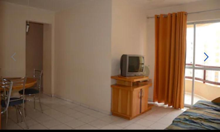 a living room with a tv on a dresser and a table with a tv at Apartamento 3 quarto com ótima área de lazer in Caldas Novas