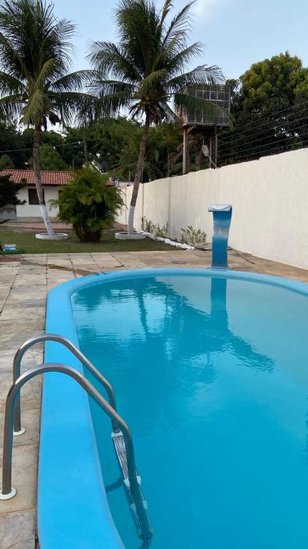 a large blue swimming pool in a yard with palm trees at Casa para temporada pertinho do mar in São José de Ribamar