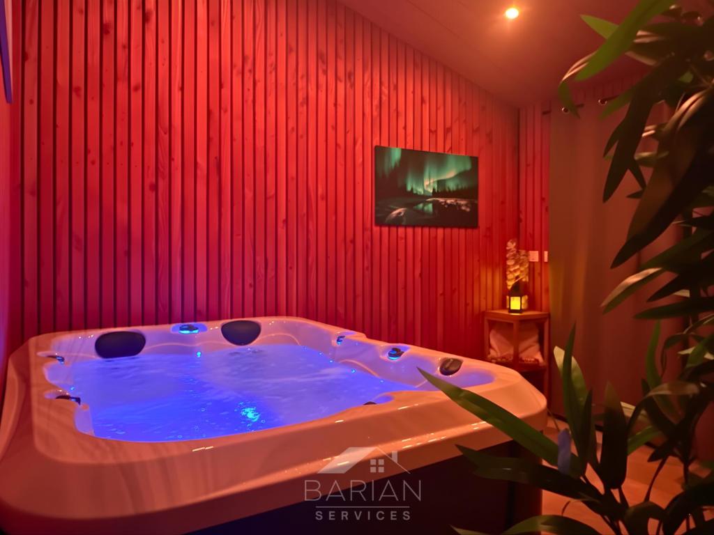 a hot tub in a room with a red wall at La Maévague - Villa 4 étoiles - Voyage entre mer et monde in Fouras