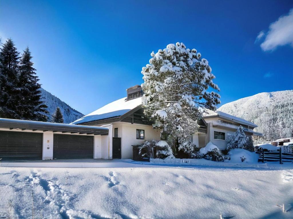 une maison avec un arbre recouvert de neige devant elle dans l'établissement An der Schiwiese, à Söll