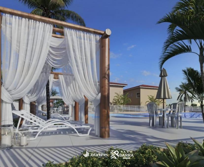 een paviljoen met witte stoelen en een parasol bij Park Barra Mais Viver in Barra dos Coqueiros