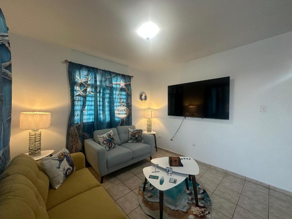 een woonkamer met een bank en een tv bij White House Paradises in Cabo Rojo