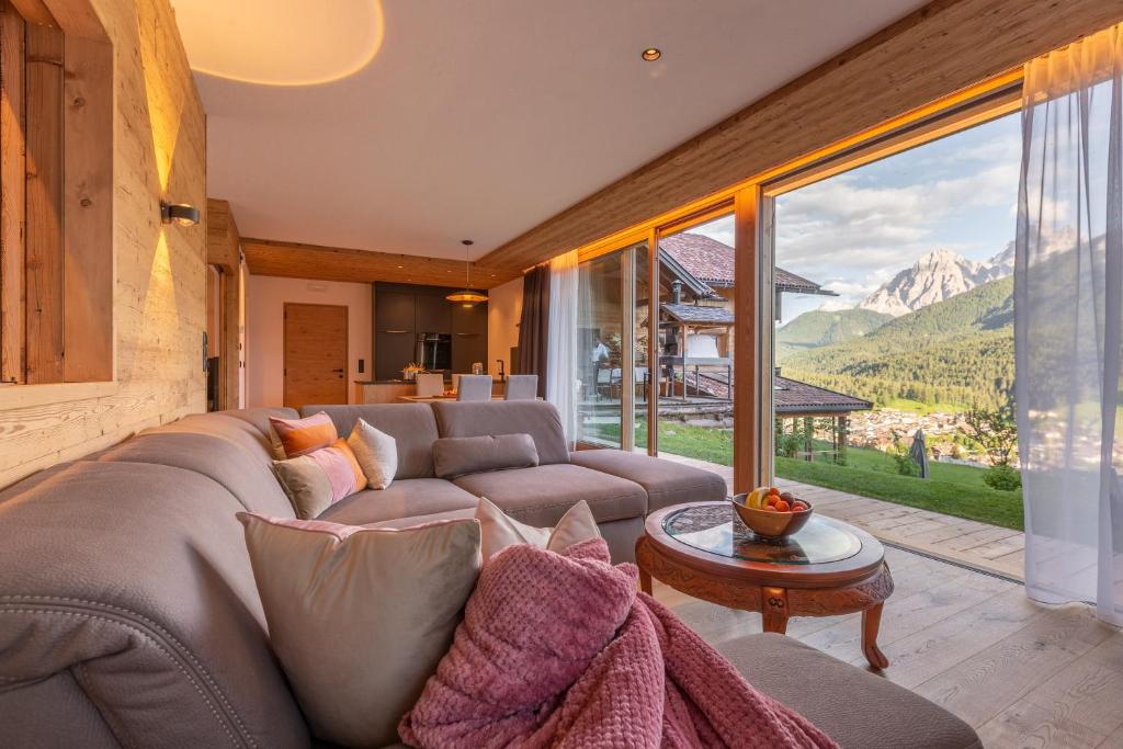 un salon avec un canapé et une grande fenêtre dans l'établissement Chalet Panorama Himmelreichhof, à San Candido