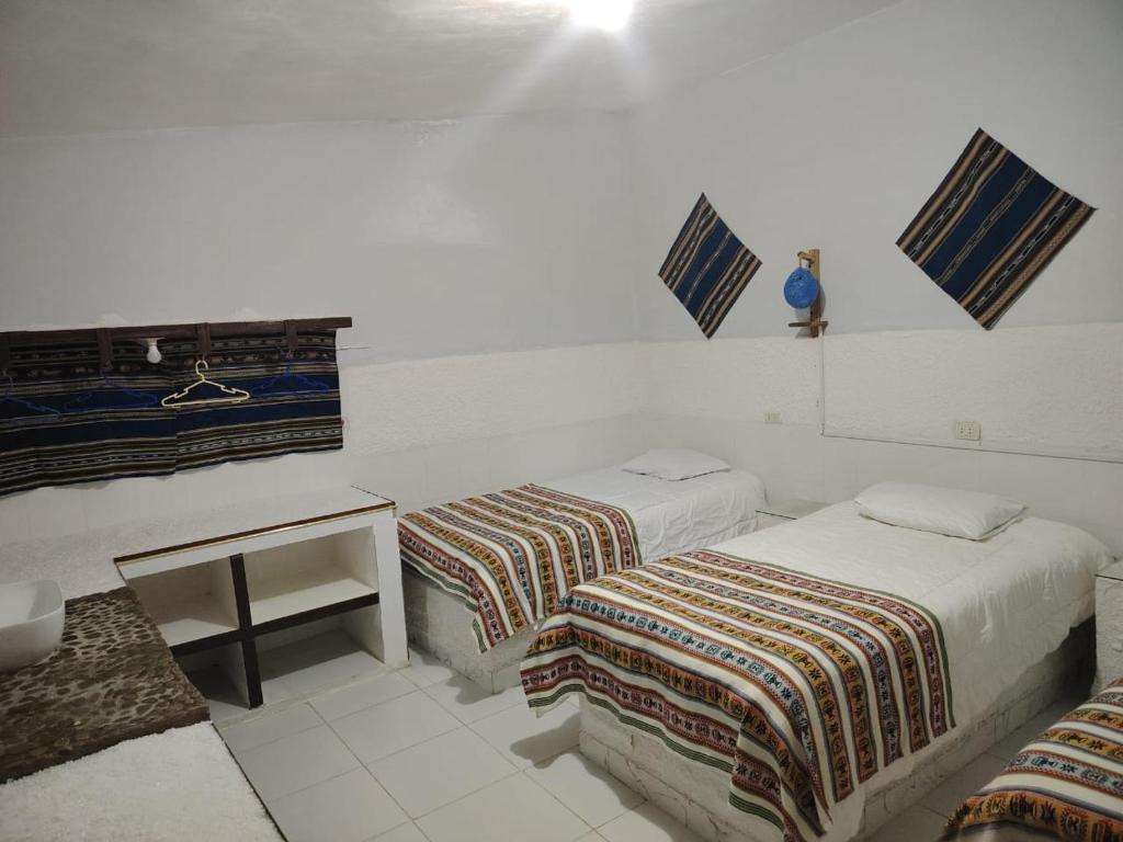 ウユニにあるCABAÑAS SAL y PIEDRAのベッド2台とテーブルがある部屋
