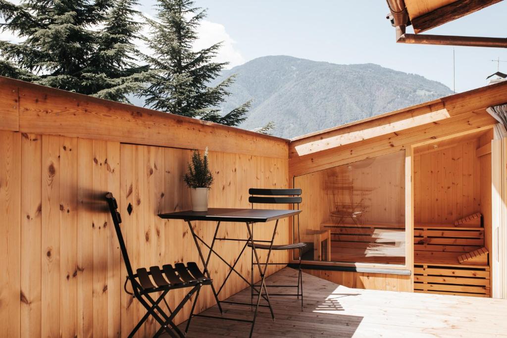 メラーノにあるAnsitz Layshof Apartment Turmの木製のフェンスにテーブルと椅子が備わるパティオ