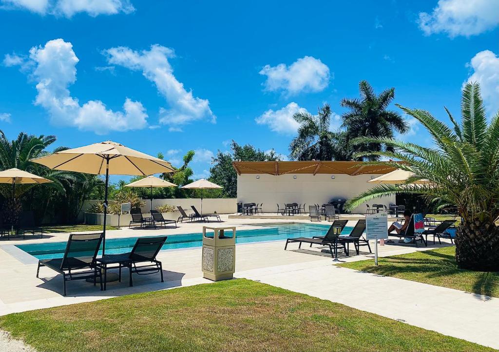 a swimming pool with chairs and umbrellas next to a pool at Maho Escape- with Pool and Gym, Lagoon view, walk to Maho Beach and Mullet Bay, walk to dinning in Maho Reef