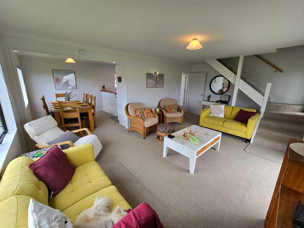 a living room with a yellow couch and a table at Hosts on the Coast Dinah & Una's Place in Whangamata