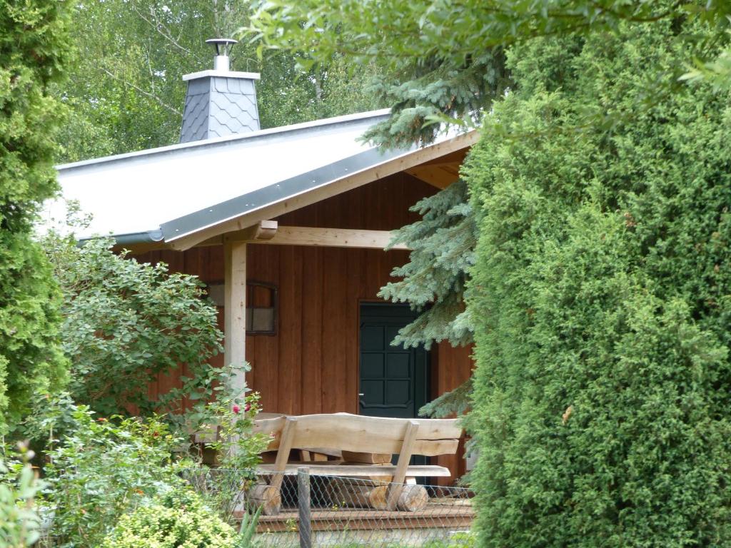 une cabane en bois avec un porche au toit blanc dans l'établissement Jagdhaus Franz, à Meßdunk