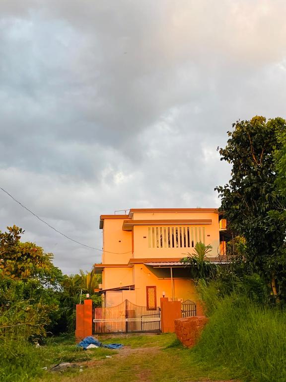 a yellow house with a fence in front of it at MO’s Agro in Pāppinisseri