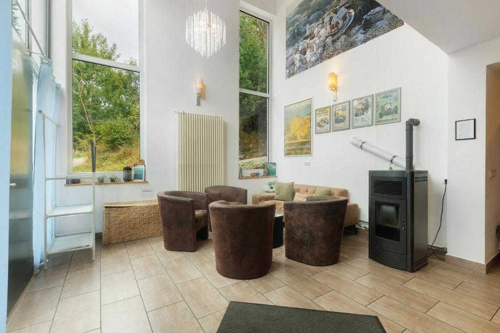 a living room with a couch and chairs and a fireplace at Ferienhaus Eifel Atrium in Zweifelscheid