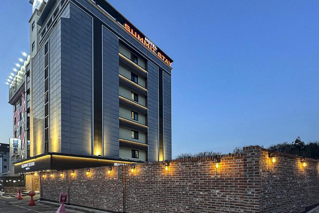 a hotel building with a brick wall in front of it at 전주 써밋스테이 