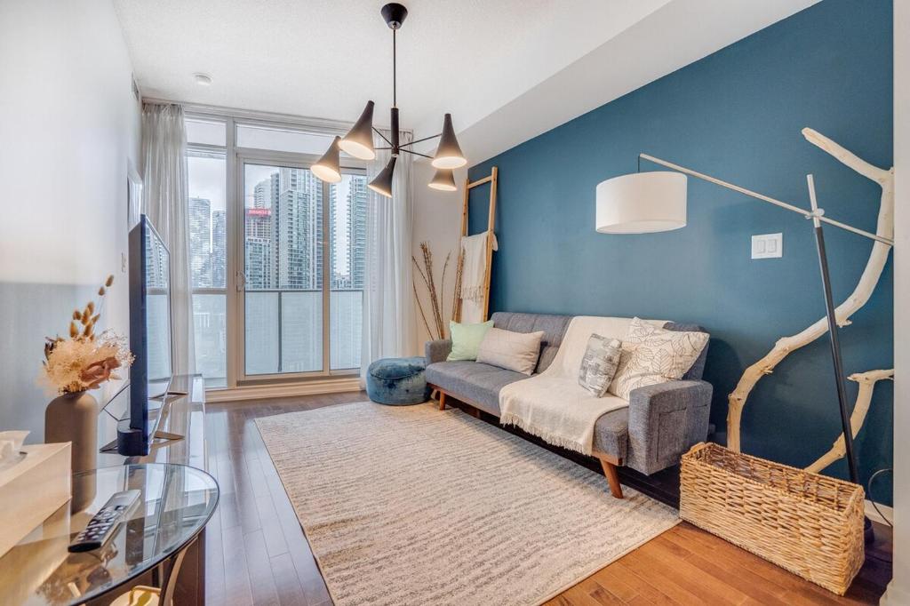 a living room with a couch and a blue wall at Modern 2 BR Condo - By Scotiabank Arena - City View in Toronto