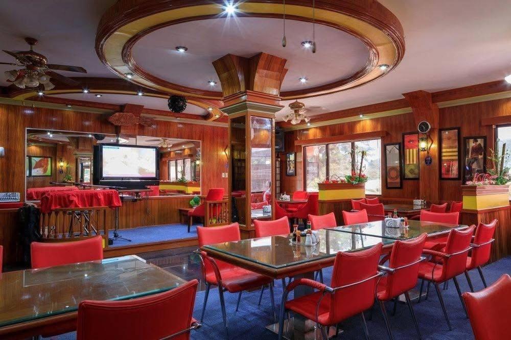 a restaurant with red chairs and tables and a television at S&C Hotel Suites and Apartments in Koror