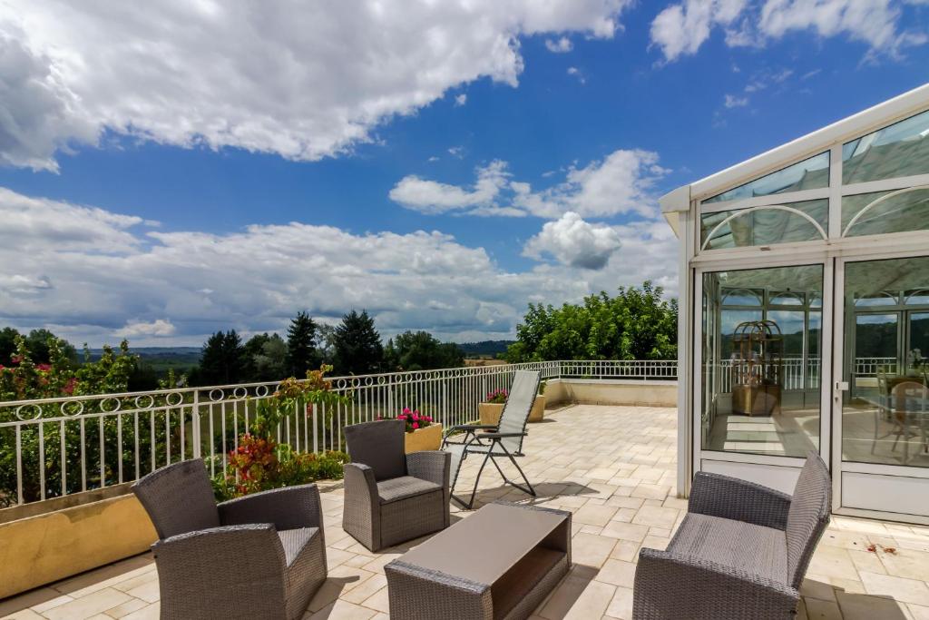 a patio with chairs and tables on a balcony at Chambre D'hôtes Vignols in Vignols
