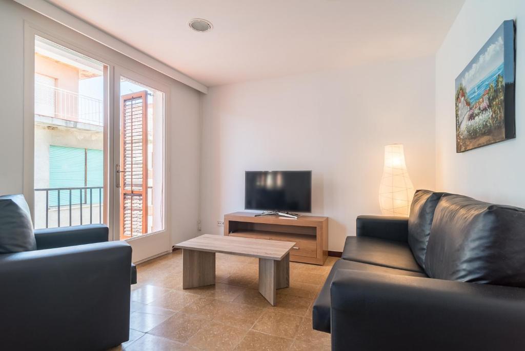 a living room with a couch and a table and a tv at Canet beach 3 in Canet de Mar