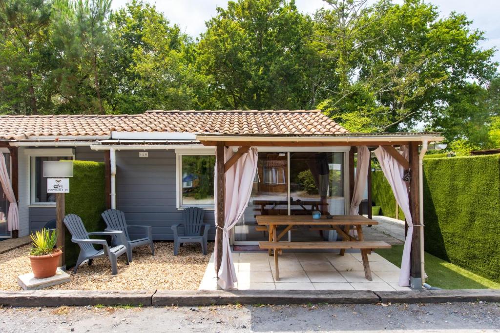 a gazebo with a wooden table and a picnic table at Chalet B Village Vacances in Gujan-Mestras