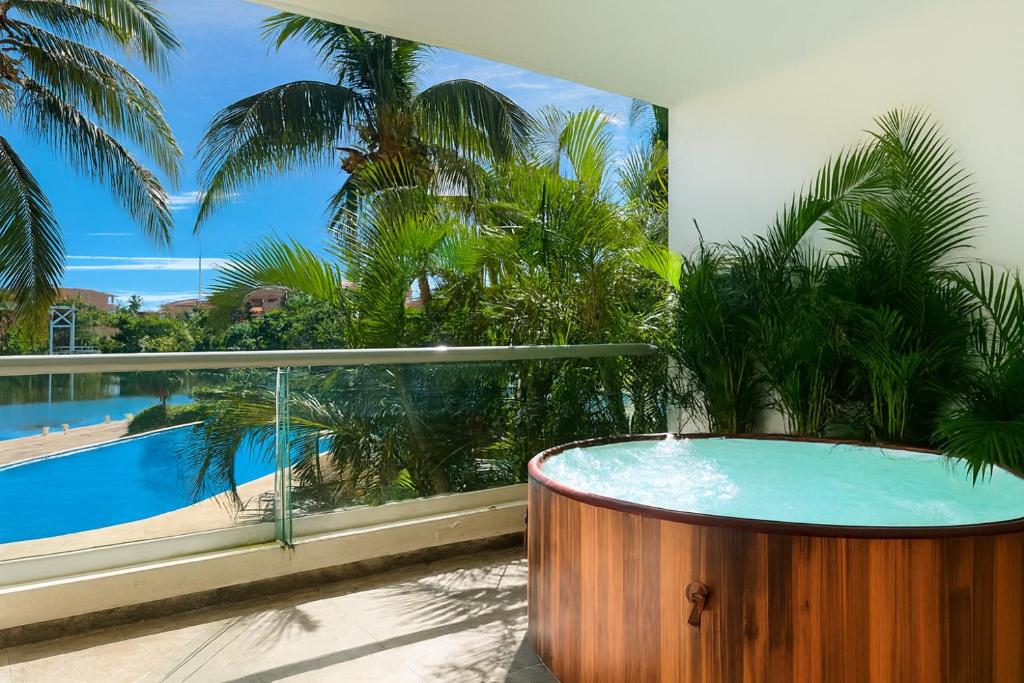 a hot tub on a balcony with a view of a pool at High-End Waterfront Condo at Secrets Waters in Puerto Aventuras