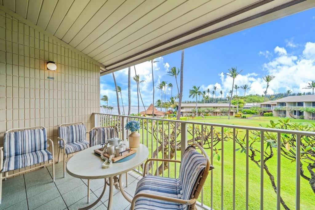 a balcony with chairs and a table and a view of a golf course at Napili Shores H262 · NS H262 BeachFront Condo Ocean Views Pool H in Kahana