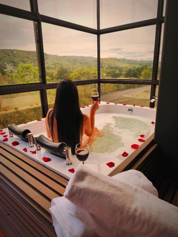 a woman sitting in a bath tub with a glass of wine at Medellin cerca al aeropuerto Rionegro Antioquia in Rionegro