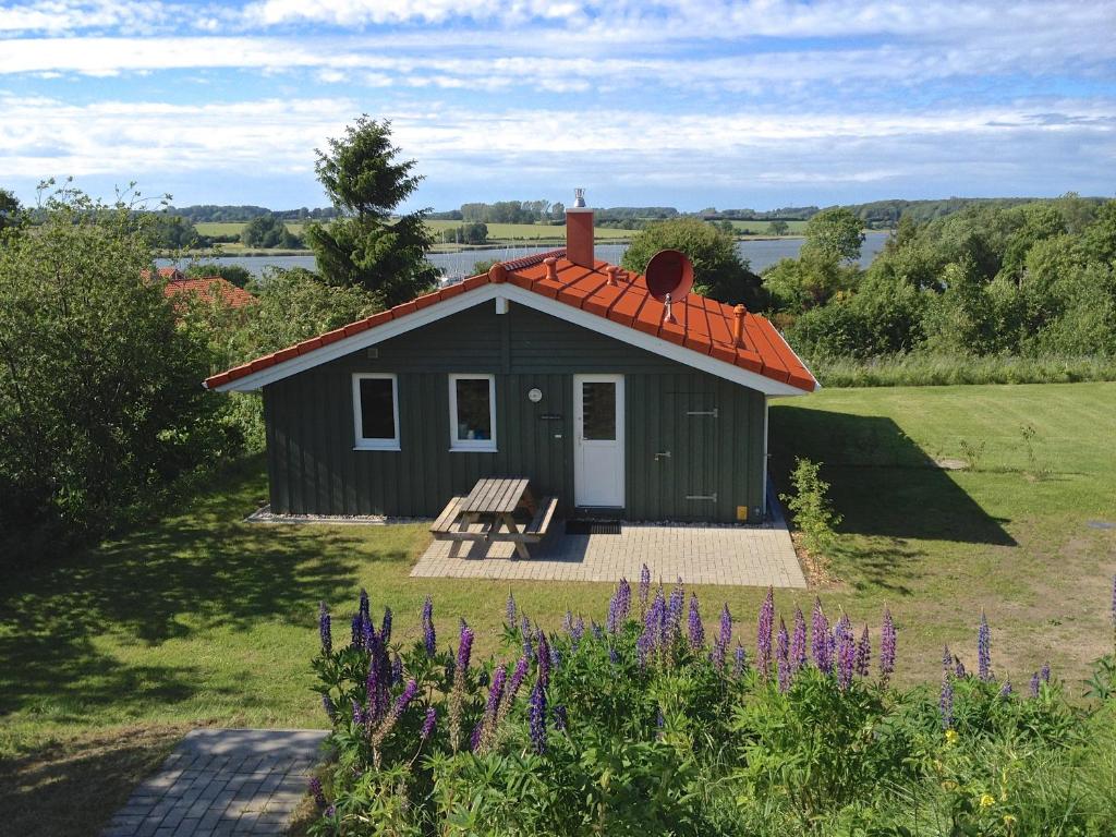 a small green building with a bench in a field at Skipper-Lodge West in Hestoft