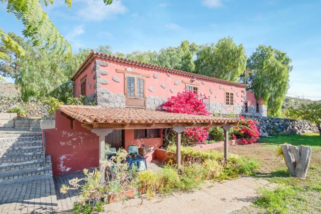 a small red house with flowers in the yard at La casita del Rincón in Arona