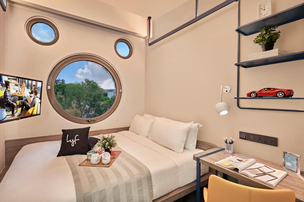 a small bedroom with a bed and a table at lyf one-north Singapore in Singapore