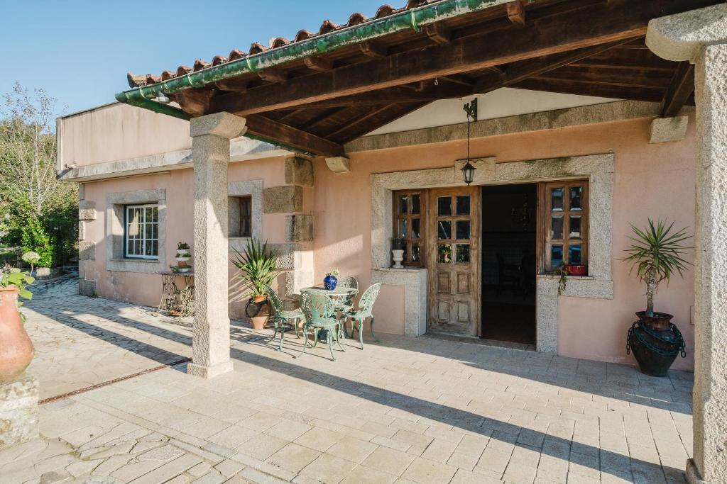 アルコス・デ・ヴァルデヴェスにあるQuinta do Passal - Gondorizの建物の前にパティオ(テーブル、椅子付)