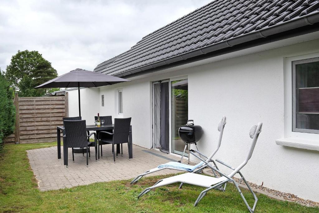 a patio with a table and chairs and an umbrella at Ferienanlage Kappeln-Kopperby in Kopperby
