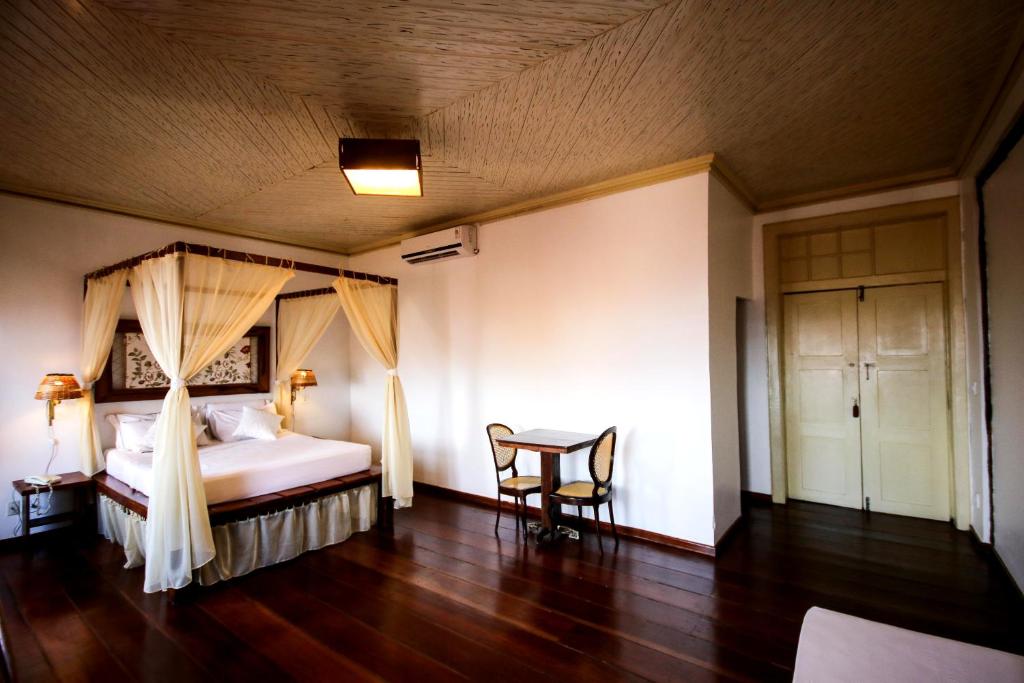 a bedroom with a bed and a chair and a table at Pousada Portas da Amazônia in São Luís