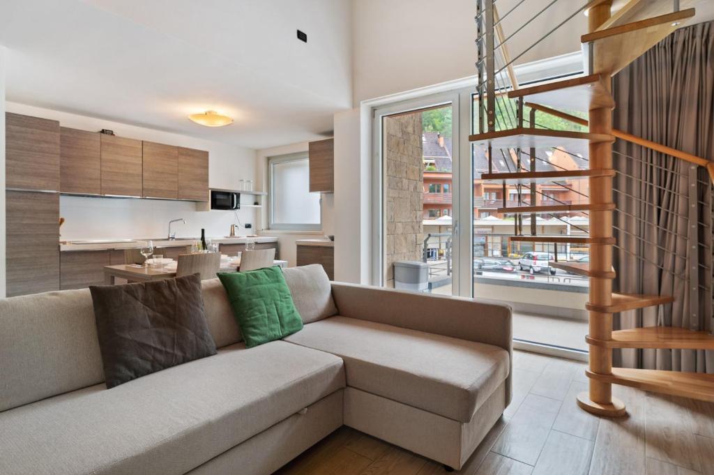 a living room with a couch and a staircase at Appartamento Jubilant in Comano Terme