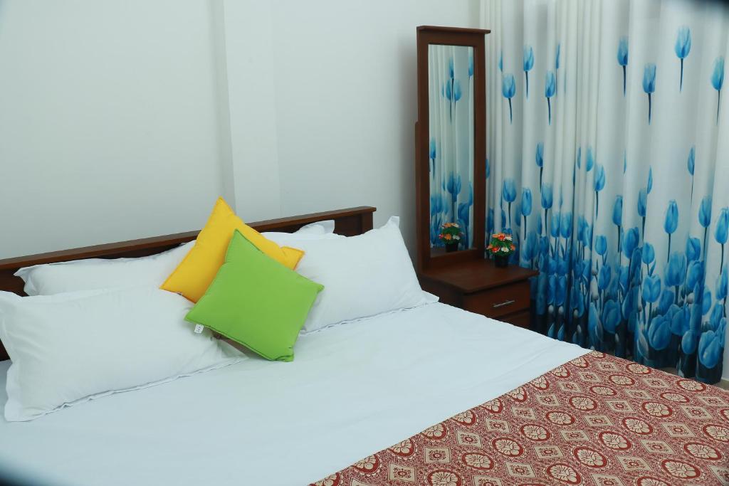 a bedroom with a white bed with colorful pillows at VILLA BLUE ROSE ,WALGAMA MADIHE Matara in Matara