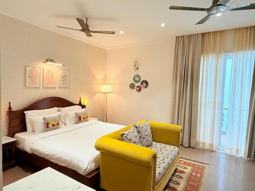 a bedroom with a bed and a yellow chair at Madhukar Vilas in Vrindāvan