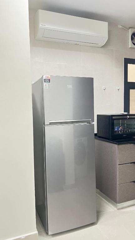 a stainless steel refrigerator in a kitchen with a microwave at مسقط العامرات in ‘Udhaybah