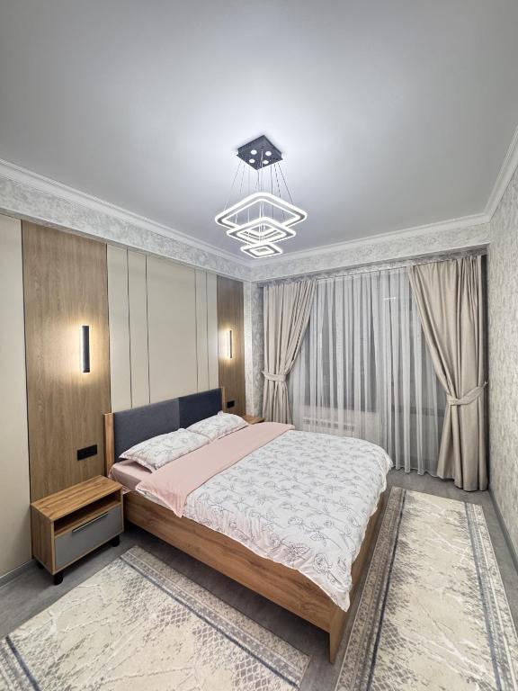 a bedroom with a large bed and a chandelier at Элеганс в Континенталь in Bishkek