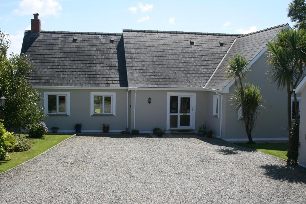 a white house with a gray roof and a gravel driveway at Pentigili in St. Davids