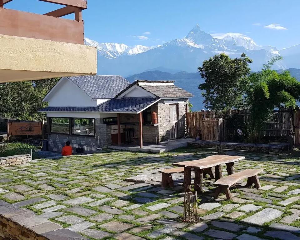 a stone patio with a picnic table in front of a house at Pumdikot Mountain Lodge in Pokhara