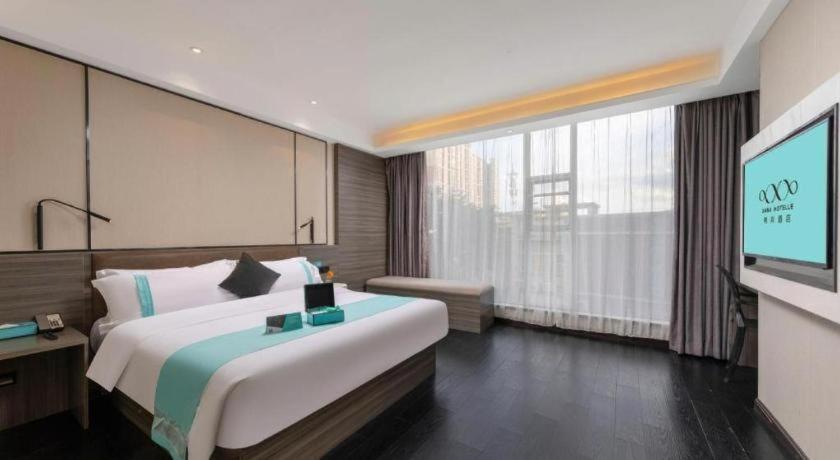 une chambre d'hôtel avec un grand lit et une télévision à écran plat dans l'établissement Xana Lite Jiangmen Yingbin West, à Jiangmen