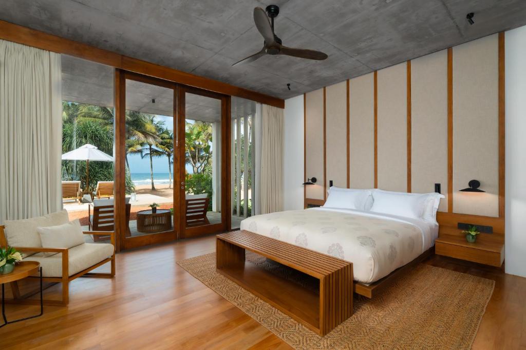 a bedroom with a bed and a couch and a table at Nyne Hotels Anugrah - Bentota in Bentota