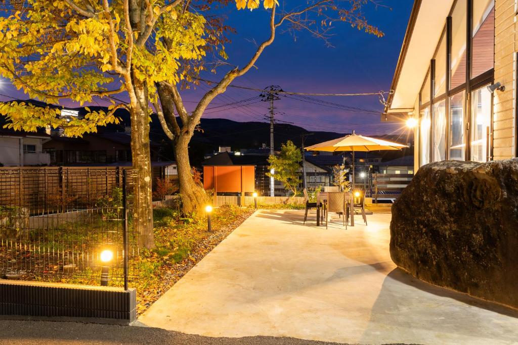 a patio with a table and an umbrella at night at 湯音の櫻 in Kusatsu