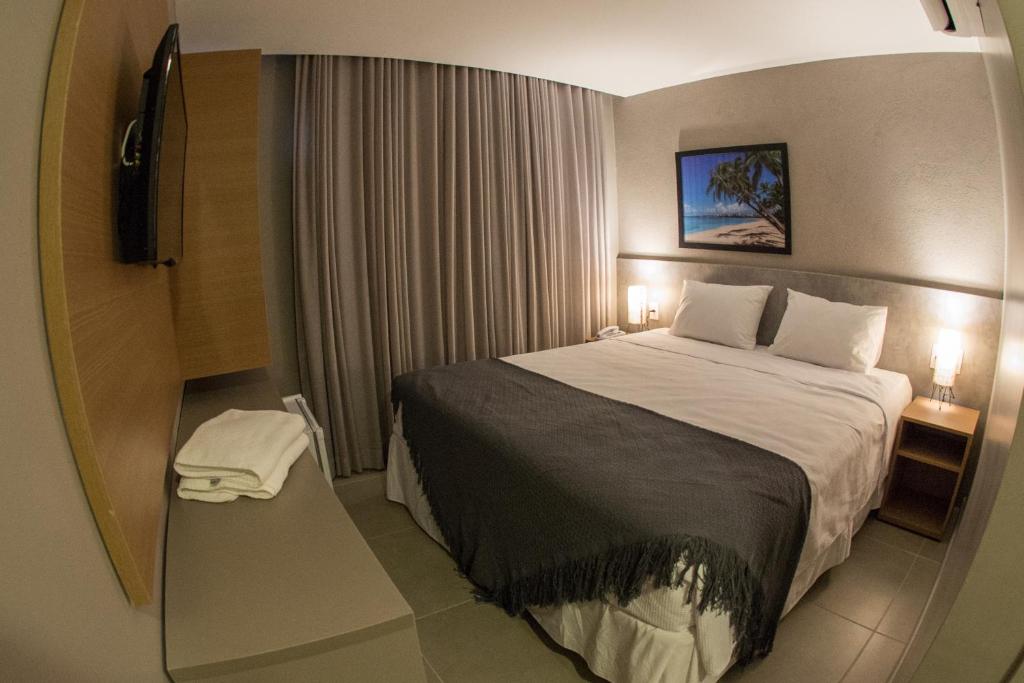 um quarto de hotel com uma cama e uma televisão em Amenit Hotel em Maceió