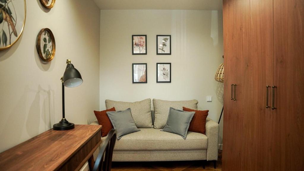 a living room with a couch and some pictures on the wall at Апарт-отель ЗОЛОТОЙ КВАДРАТ premium in Almaty